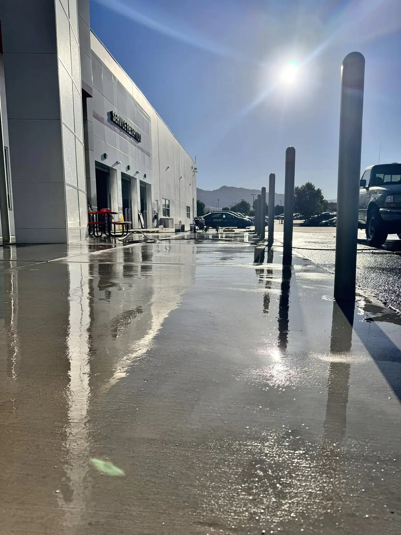 Freshly pressure washed concrete outside a commercial building, wet and reflective in the sun